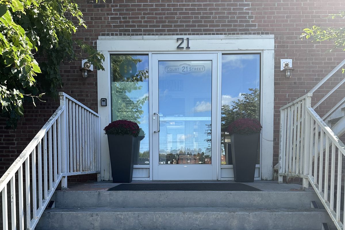 The front entrance of 21 Court Street in Canton, New York — a brick building with glass doors and a large 21 above the entry